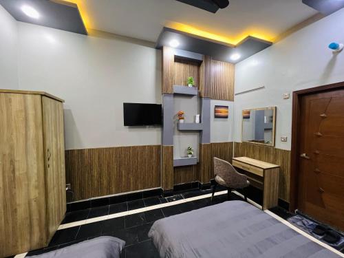 a room with a bed and a desk and a tv at Karachi Inn in Karachi
