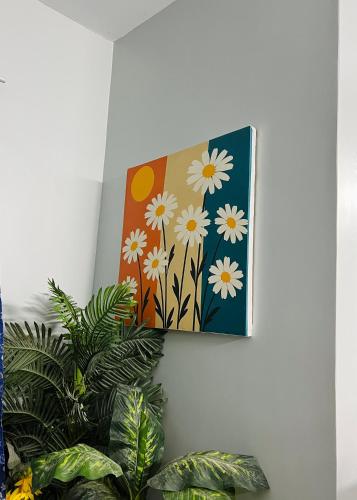 a painting of flowers on a wall next to a plant at Karachi Inn in Karachi