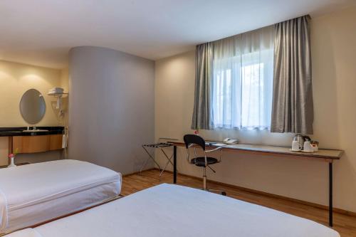 a hotel room with a bed and a desk and a window at Best Western Nairobi Upper Hill in Nairobi
