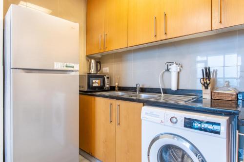 a kitchen with a white refrigerator and a washing machine at Live in the center of Mountains, Sea, Mangroves in Ras al Khaimah