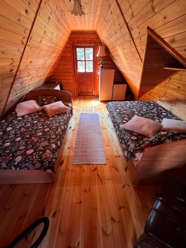a room with two beds in a wooden cabin at Hello Kurpie in Nowogród