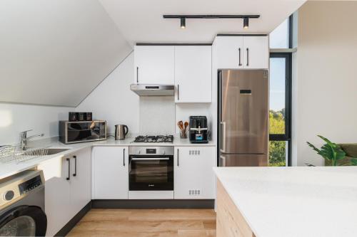 a kitchen with white cabinets and a stainless steel refrigerator at St Francis Links - Elegant, Golfside & Coastal Apartment in St Francis Bay