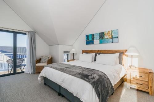a bedroom with a large bed and a balcony at St Francis Links - Elegant, Golfside & Coastal Apartment in St Francis Bay