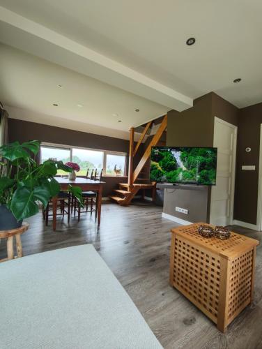 a living room with a television and a table with chairs at Vakantiehuisje 'De Uithof' in Oosterhesselen