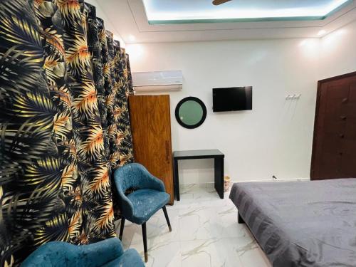 a bedroom with a bed and a chair and a curtain at Karachi Inn in Karachi