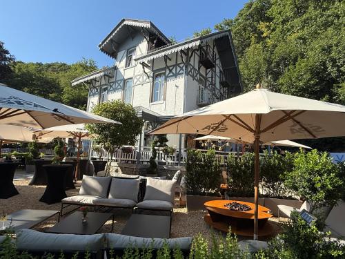 a patio with couches and umbrellas in front of a building at Hotel La Tonnellerie in Spa