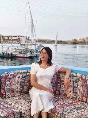 a woman sitting on a couch next to the water at DoroKa Nubian House in Aswan