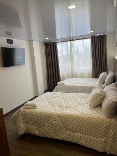a bedroom with two beds and a flat screen tv at BOG Living Suites in Bogotá