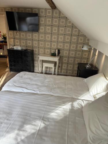 a bedroom with a white bed and a tv on a wall at Hotel La Tonnellerie in Spa