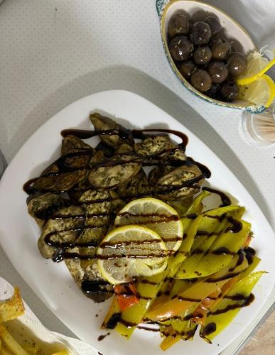 a plate of food with pickles and a bowl of grapes at Golden Campsite Villas in Berat