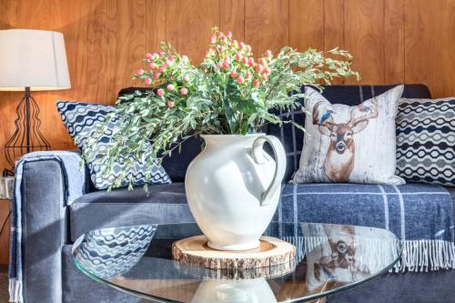 a blue couch with a vase on a glass table at Huckleberry Lodge Mountain Getaway Near Banff in Canmore
