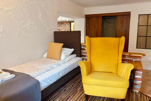 a yellow chair and a bed in a room at Pod Wzgórzem Bed & Breakfast in Frombork