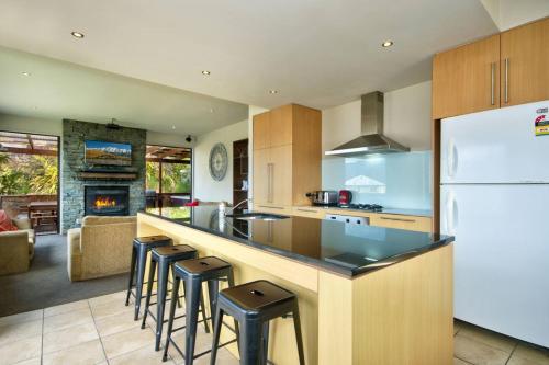 a kitchen with a counter with stools and a refrigerator at Lakeview Lodge Two with Stunning Views in Queenstown