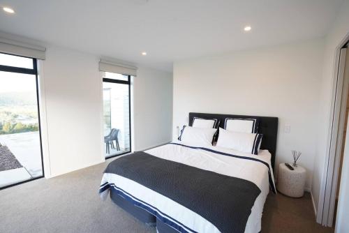 a bedroom with a large bed with white walls and windows at Northland Nest By Aotearoa Escapes in Whangarei