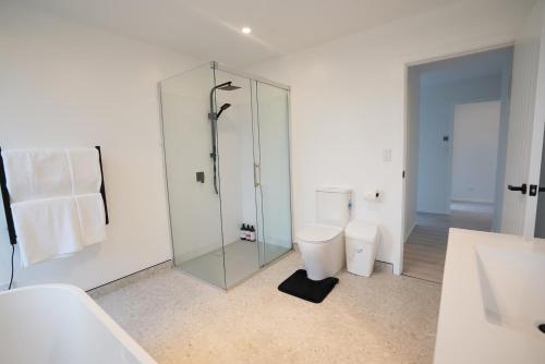 a bathroom with a glass shower and a toilet at Northland Nest By Aotearoa Escapes in Whangarei