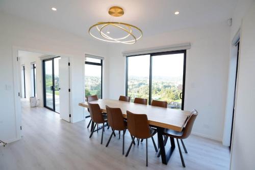 a dining room with a table and chairs and windows at Northland Nest By Aotearoa Escapes in Whangarei