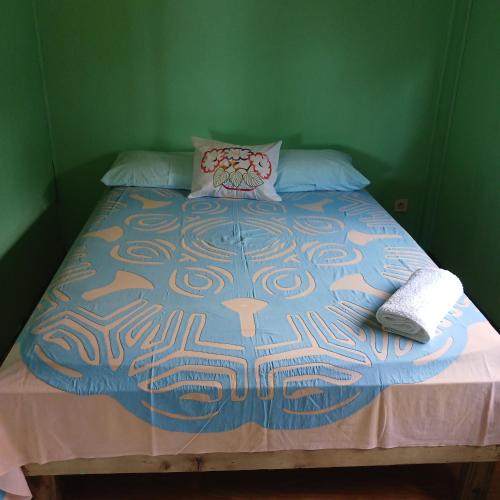 a bed in a green room with a colorful bedspread at Hoakehu Lodge hoakua in Nuku Hiva