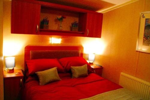 a bedroom with a red bed with two lights on it at Island Bordeaux in Isle of Wight