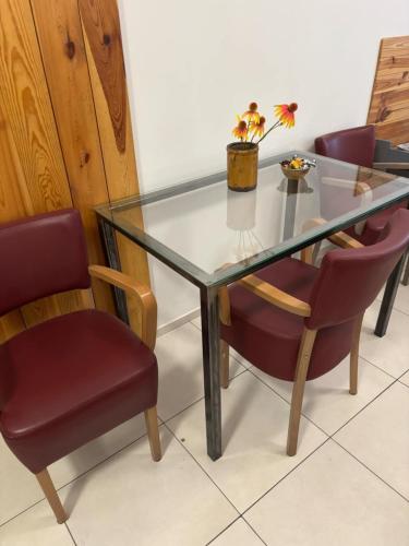 una mesa de cristal con sillas y un jarrón con una planta en Buko apartamenty, en Uniejów