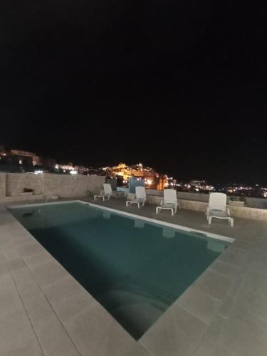 a swimming pool at night with chairs and lights at Villa Nunzia in Ostuni