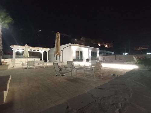 a patio with chairs and a table and umbrellas at night at Villa Nunzia in Ostuni