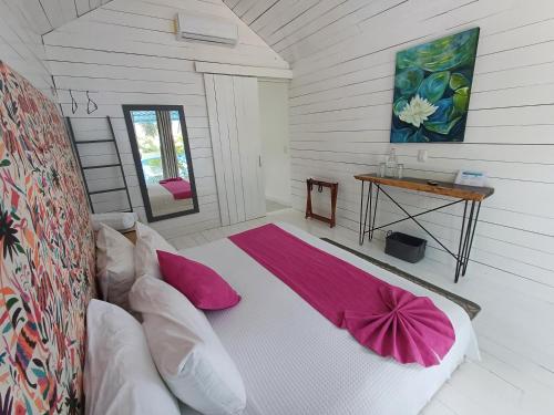 a bedroom with a bed with pink pillows on it at Zensus Eco Boutique Hotel in Bacalar