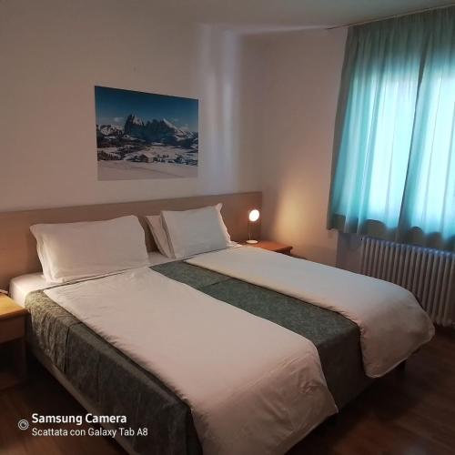 a bedroom with a large bed with blue curtains at Life Hotels Des Alpes in Folgaria