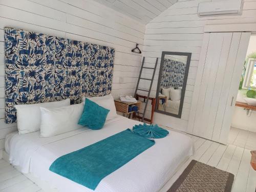 a bedroom with a white bed with a blue headboard at Zensus Eco Boutique Hotel in Bacalar