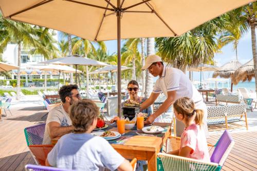 Un groupe de personnes assises autour d'une table à la plage dans l'établissement Garza Blanca Resort & Spa Cancun, à Cancún