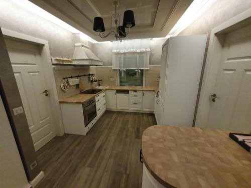 a kitchen with white cabinets and a table in it at Sosenkowe Apartamenty in Kuźnica Głogowska