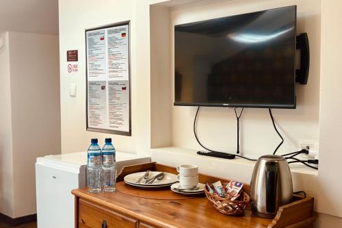 a television on a wall with a table with drinks on it at Pod Wzgórzem Bed & Breakfast in Frombork