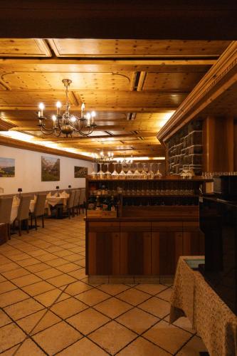 a dining room with a bar and tables and a chandelier at Hotel Marlingerhof in Marlengo