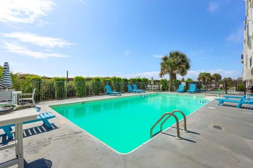 a large swimming pool with blue chairs and a table at Carolina Beach Condo with Marina View, on Boardwalk in Carolina Beach