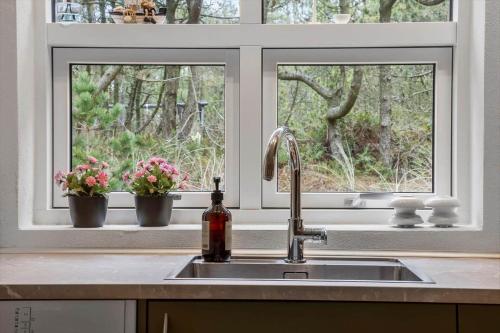 a kitchen with a sink and two windows with flowers at 873-Thisted-Blamunkevej-67 in Thisted