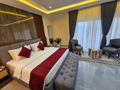 a bedroom with a large bed and two chairs at Reens Suites and Apartments in Port Harcourt