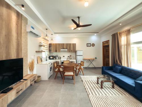 a living room with a blue couch and a kitchen at Twin Villa Zulia by Zanzibar Stays - Private Pool Villa Jambiani in Jambiani