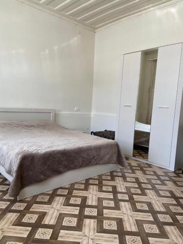 una camera da letto bianca con un letto e uno specchio di Дом в центре a Gyumri