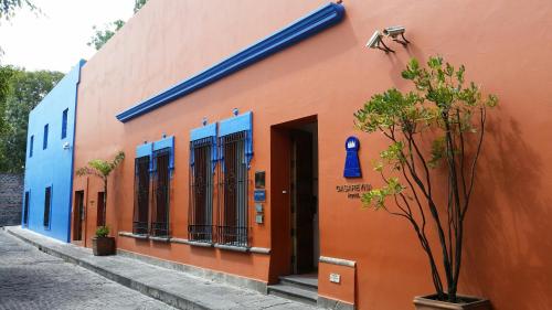 an orange building with blue windows on a street at Hotel Boutique Casareyna in Puebla