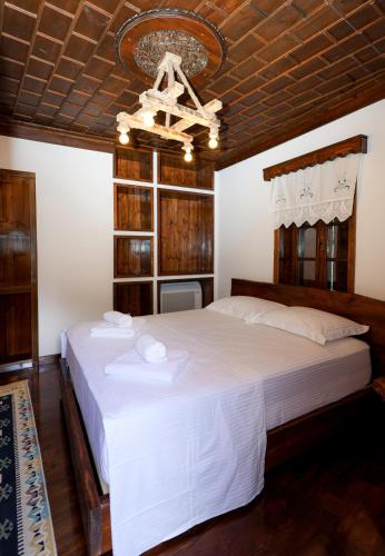 a bedroom with a large white bed with a chandelier at Oda e Gurit - Boutique Hotel in Berat