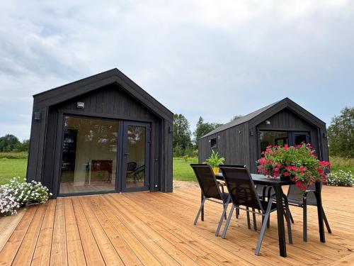 a black shed with a table and chairs on a deck at Rātes Krasti - Rasa - holiday house with sauna and lakeview in Lejasciems