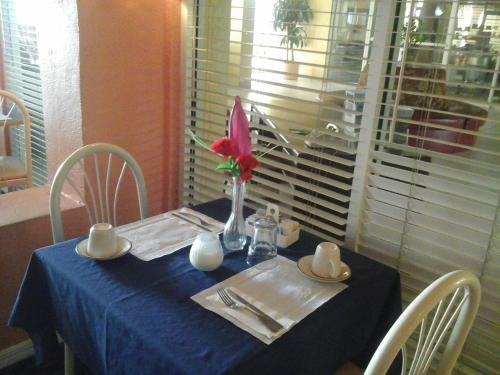a table with a blue table cloth and a vase with a red flower at Royal Islander Hotel in Freeport