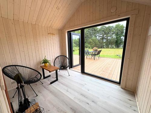 a screened in porch with a table and chairs at Rātes Krasti - Rasa - holiday house with sauna and lakeview in Lejasciems