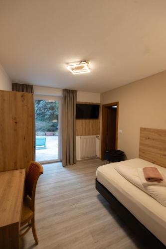 a bedroom with a bed and a table and a window at Hotel Marlingerhof in Marlengo