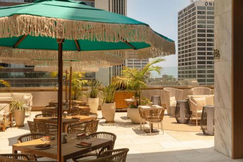 a patio with tables and chairs and a green umbrella at The Delphi Downtown LA in Los Angeles