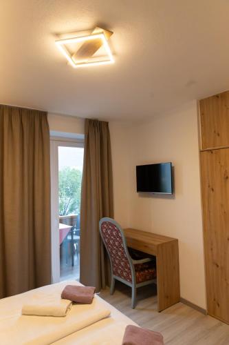 a hotel room with a bed and a desk and a television at Hotel Marlingerhof in Marlengo
