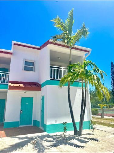 a white house with palm trees in front of it at Bimini Tides in South Bimini