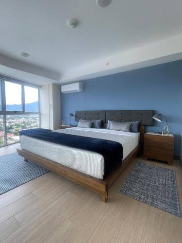 a bedroom with a large bed with a blue wall at Exclusive apartment in downtown Costa Rica in San José