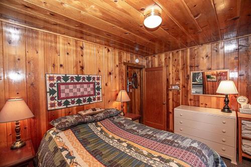 - une chambre avec des murs en bois, un lit et deux lampes dans l'établissement Fir Forest Cottage By Hauserman Rentals, à Tahoe City