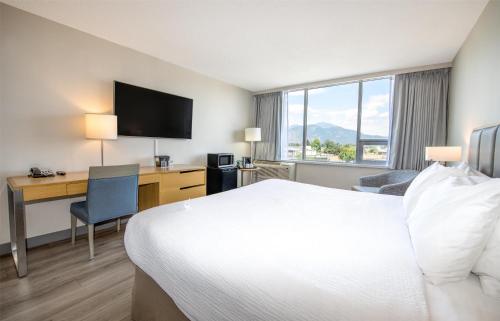 a hotel room with a bed and a desk with a computer at Coast Chilliwack Hotel by APA in Chilliwack