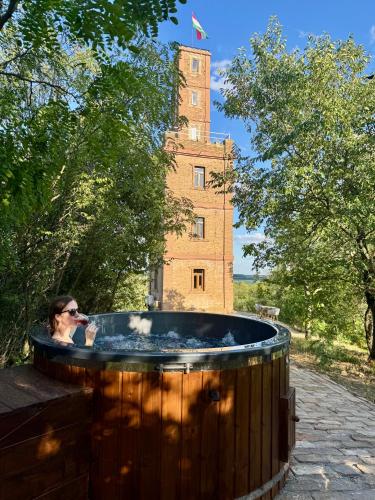 a woman standing in a hot tub in front of a building at Söréttorony - A jakuzzis erdei szállás in Kölesd